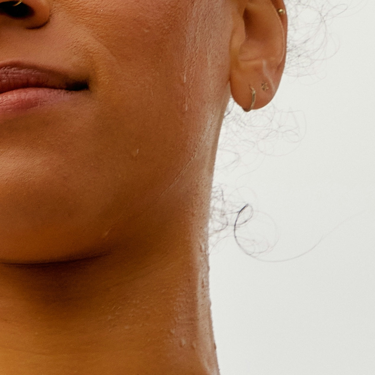 Close-up of a person's wet neck and jawline with water droplets, suggesting hydration or sweating.
